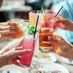 Ludzie wznoszą toast kolorowymi drinkami. Czy zastanawiasz się, jak kreatyna a alkohol wpływają na formę?