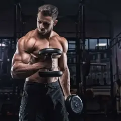 Mięśniak ćwiczy biceps z hantlami. Zastanawia się, ile serii na biceps wykonać dzisiaj, by osiągnąć najlepsze rezultaty.